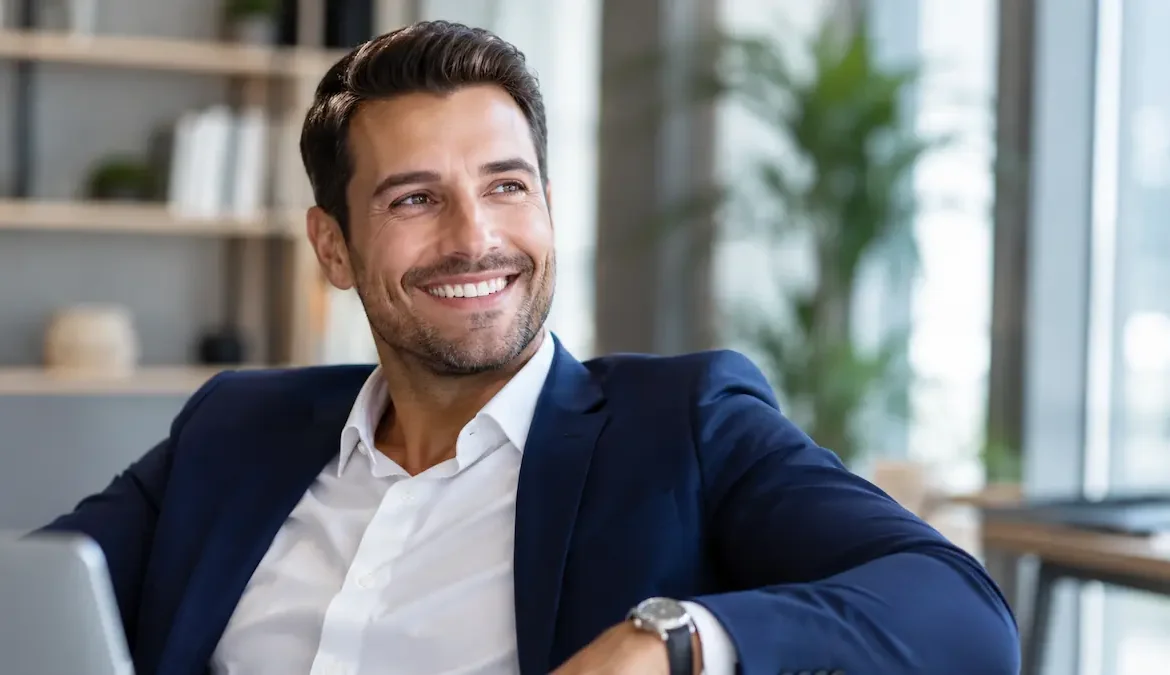 Bărbat profesionist zâmbind într-un birou modern, ilustrând beneficiile restaurării dentare complete cu implanturi și recâștigarea încrederii în sine.